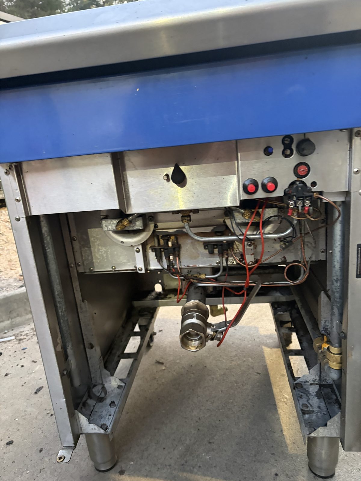 Fryer burner bay after cleaning, second angle — burner tubes, gas valve and thermostat wiring clean
