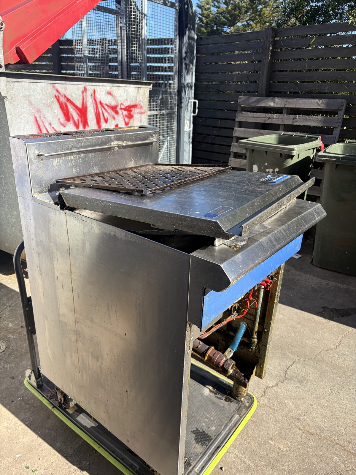 Three-quarter view of the dirty commercial fryer on a trolley outside the club's back-of-house area