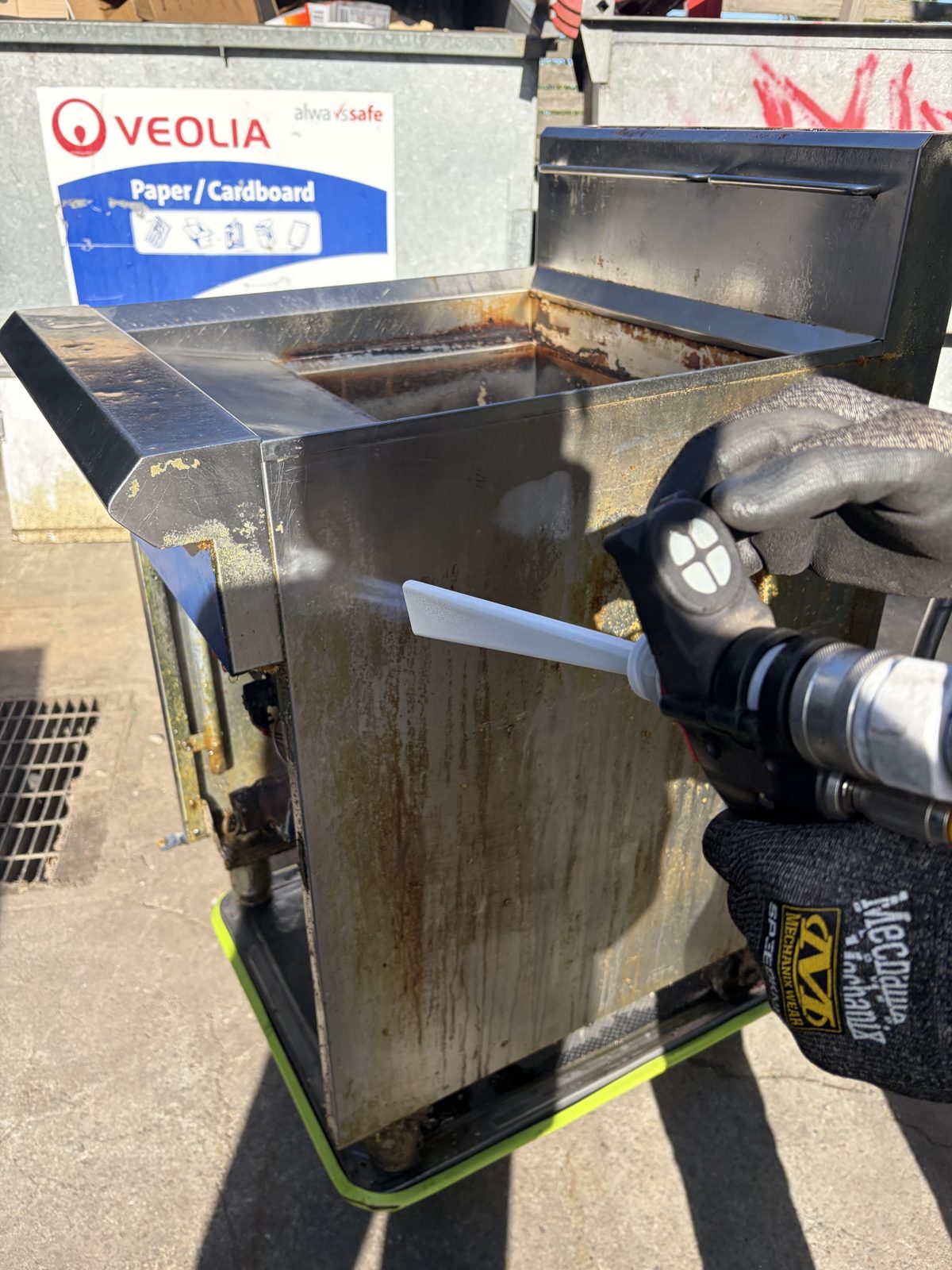 Close-up of the nozzle lifting carbonised grease from the fryer side panel