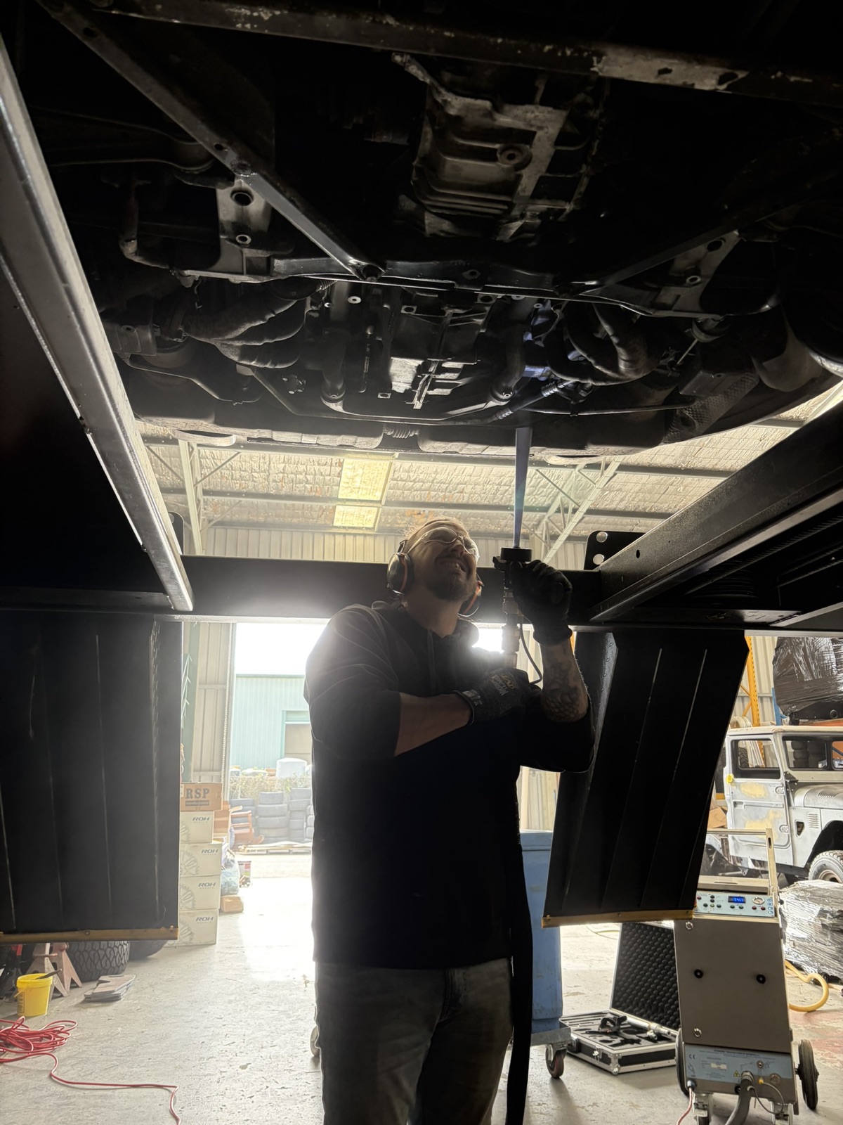 Operator under the lift working the rear of the car